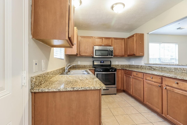 kitchen featuring light stone countertops, sink, light tile patterned floors, and appliances with stainless steel finishes