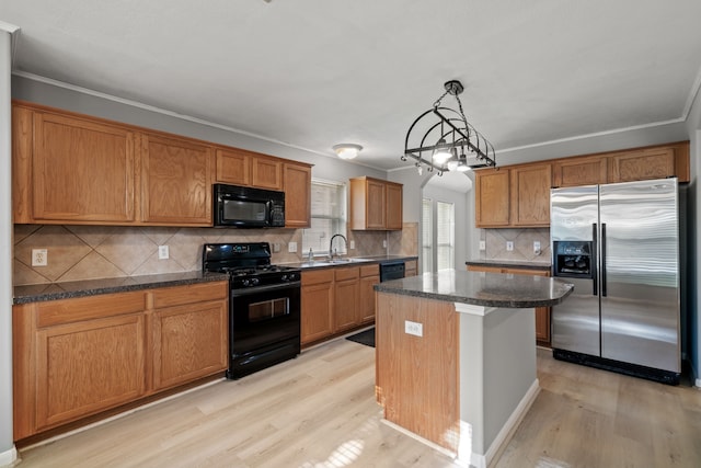 kitchen with black appliances, a kitchen island, light wood-type flooring, and a sink