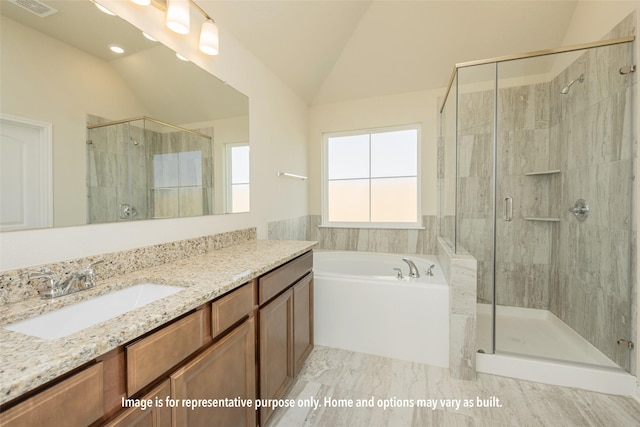 bathroom featuring vanity, independent shower and bath, and vaulted ceiling