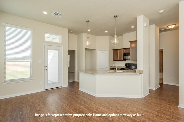 kitchen with sink, dark wood-type flooring, hanging light fixtures, light stone counters, and black appliances