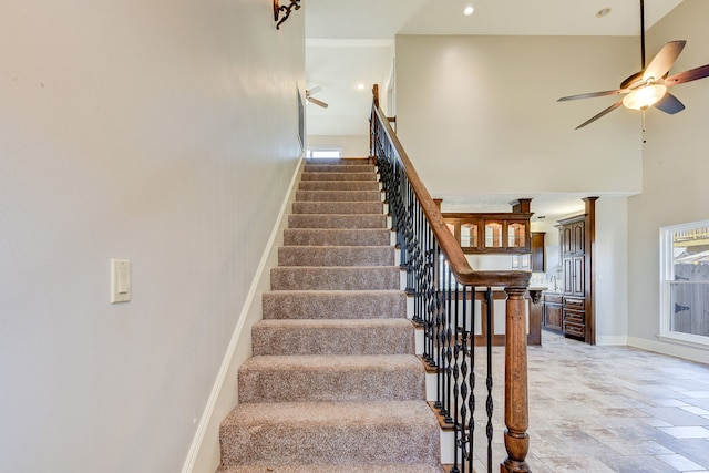 stairs with ceiling fan and a high ceiling