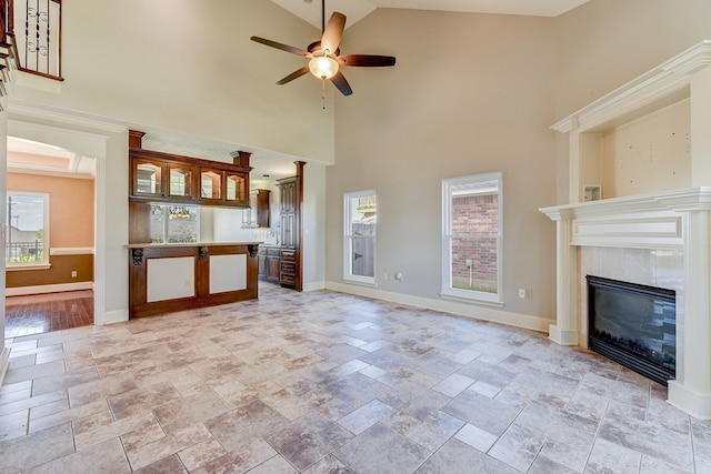 unfurnished living room with a wealth of natural light, a tile fireplace, high vaulted ceiling, and ceiling fan