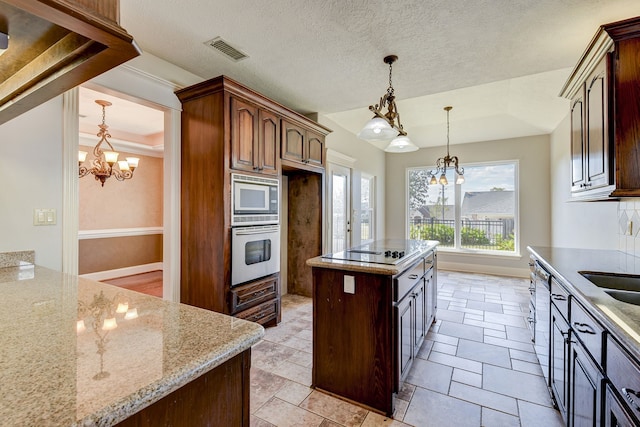 kitchen featuring light stone countertops, dark brown cabinets, a center island, stainless steel appliances, and an inviting chandelier