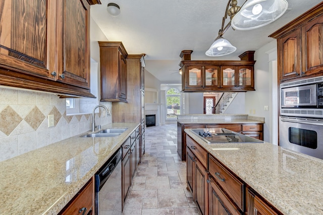 kitchen with stainless steel appliances, sink, light stone countertops, pendant lighting, and tasteful backsplash