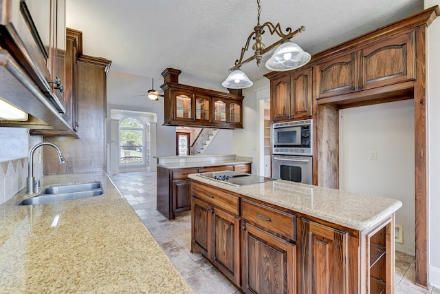 kitchen featuring sink, a center island, pendant lighting, appliances with stainless steel finishes, and a textured ceiling