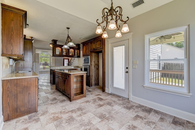 kitchen with sink, decorative light fixtures, plenty of natural light, and a kitchen island