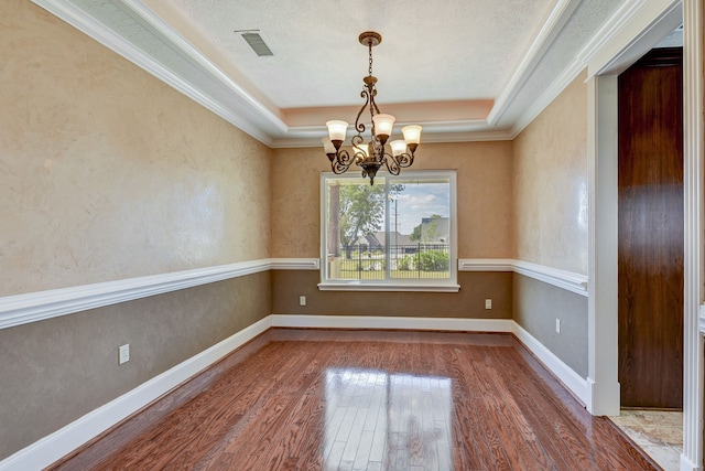 spare room with hardwood / wood-style floors, a chandelier, and a raised ceiling