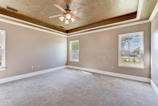 unfurnished room featuring ceiling fan, a raised ceiling, a textured ceiling, carpet flooring, and crown molding