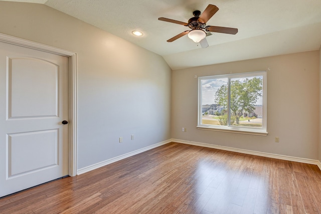 empty room featuring a textured ceiling, hardwood / wood-style flooring, ceiling fan, and vaulted ceiling