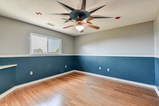 empty room featuring a textured ceiling, light wood-type flooring, and ceiling fan