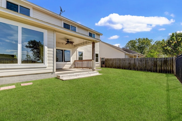 back of house with a wooden deck, a lawn, and ceiling fan