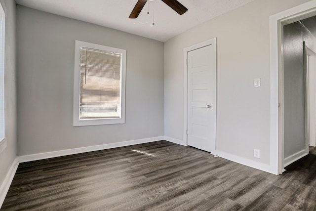 unfurnished bedroom with ceiling fan and dark wood-type flooring