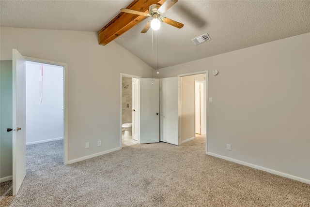 unfurnished bedroom featuring connected bathroom, light colored carpet, lofted ceiling with beams, and a textured ceiling