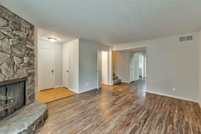 unfurnished living room with a fireplace, light hardwood / wood-style flooring, and a textured ceiling