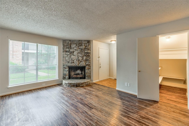 unfurnished living room with wood-type flooring, a textured ceiling, and a fireplace