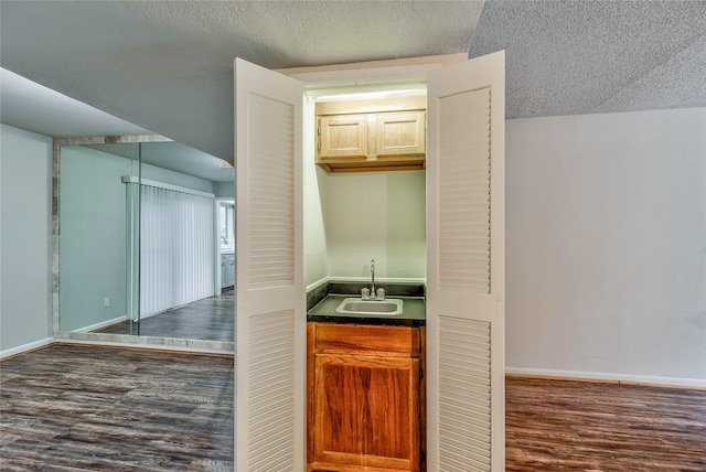 hallway featuring sink, dark wood-type flooring, and a textured ceiling