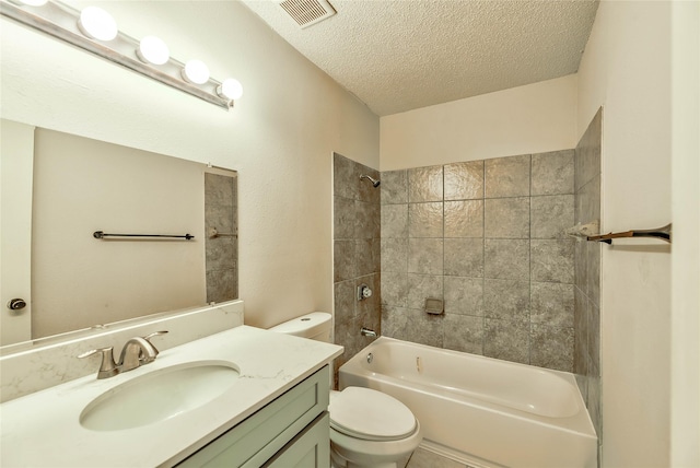 full bathroom featuring tiled shower / bath, vanity, toilet, and a textured ceiling