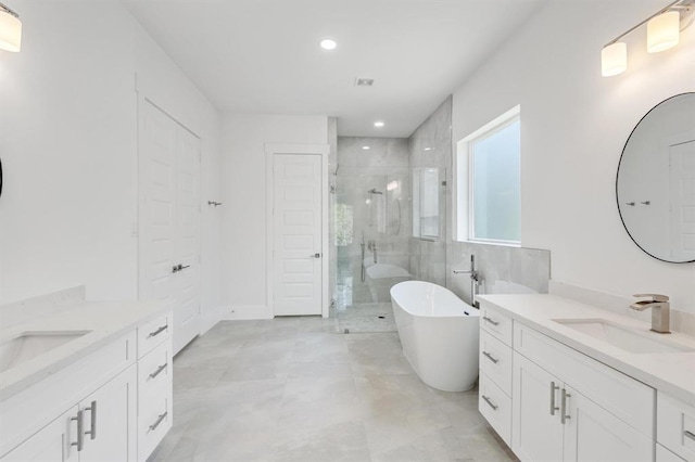 bathroom with a soaking tub, two vanities, recessed lighting, a stall shower, and a sink