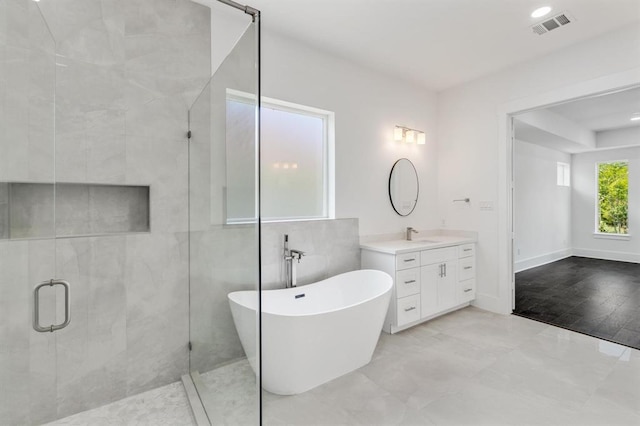 bathroom featuring vanity, baseboards, visible vents, a freestanding tub, and a stall shower