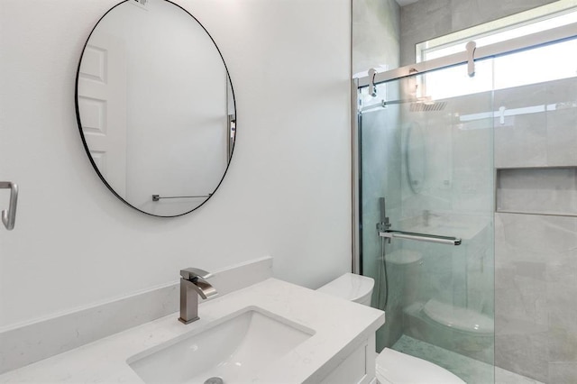 bathroom featuring vanity, toilet, and a shower with shower door