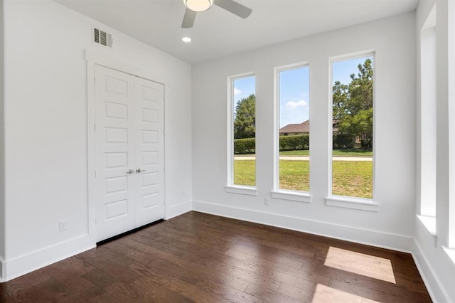 unfurnished bedroom featuring dark hardwood / wood-style flooring, ceiling fan, a closet, and multiple windows