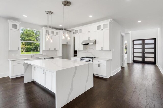 kitchen featuring a center island, light stone counters, white cabinetry, and sink