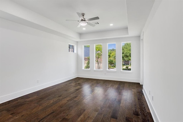 spare room featuring a raised ceiling, ceiling fan, and dark hardwood / wood-style floors