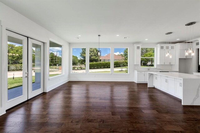 kitchen featuring light stone countertops, french doors, dark wood-type flooring, pendant lighting, and white cabinets