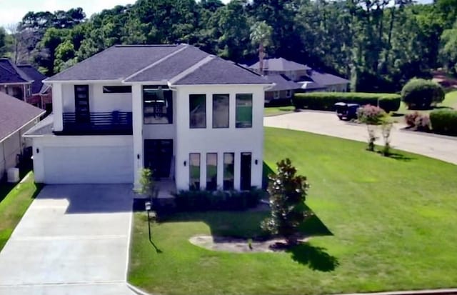 view of front of property with stucco siding, an attached garage, concrete driveway, and a front lawn