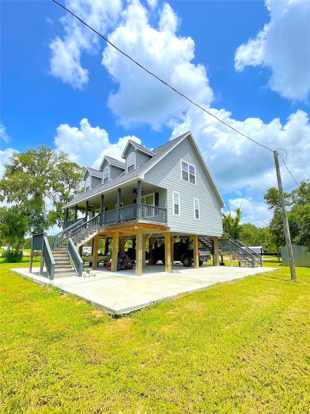 rear view of house featuring a carport, ceiling fan, a porch, and a lawn