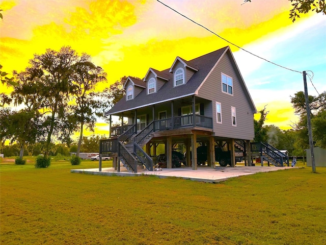 back house at dusk with covered porch and a yard