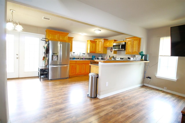 kitchen with sink, stainless steel appliances, kitchen peninsula, plenty of natural light, and a kitchen bar