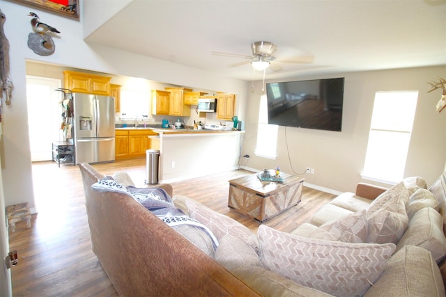 living room with ceiling fan, light hardwood / wood-style floors, and sink