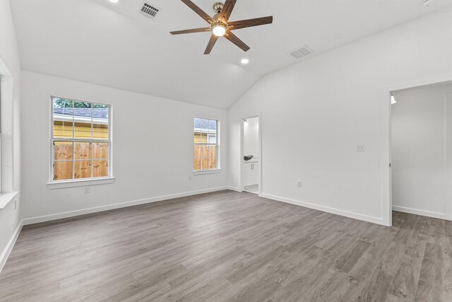 empty room featuring plenty of natural light, ceiling fan, light wood-type flooring, and lofted ceiling