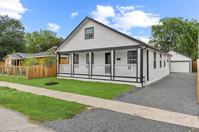 view of front of property with covered porch, a garage, a front lawn, and an outdoor structure