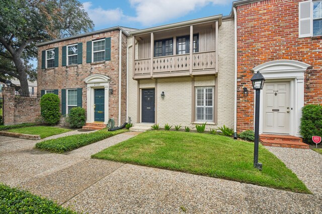 view of property featuring a balcony and a front yard