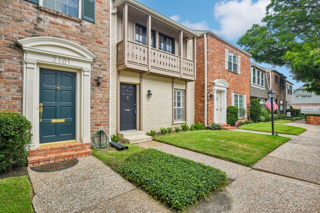 view of front of property with a balcony and a front yard