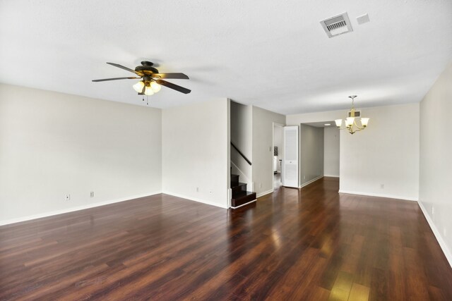 empty room featuring ceiling fan with notable chandelier and dark hardwood / wood-style floors