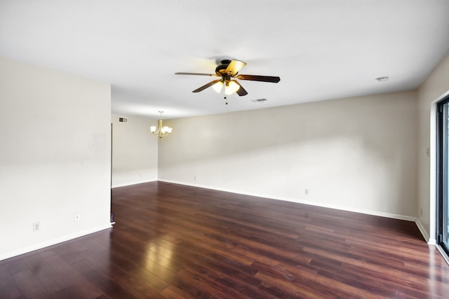 empty room featuring dark hardwood / wood-style flooring and ceiling fan with notable chandelier