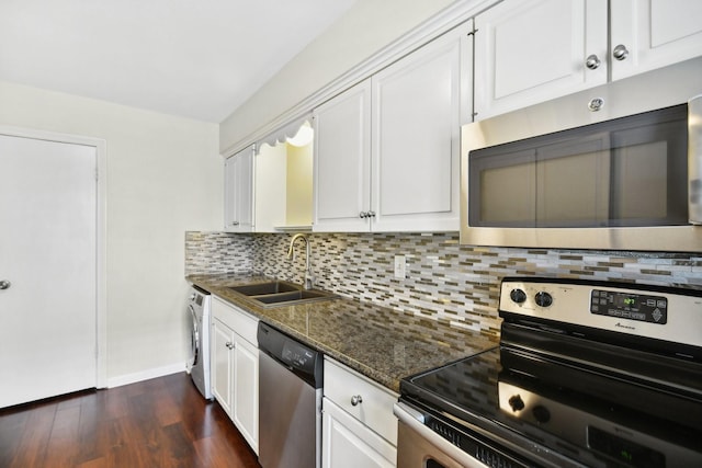 kitchen featuring white cabinetry, sink, dark stone countertops, washer / dryer, and appliances with stainless steel finishes