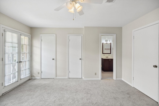 unfurnished bedroom with light carpet, two closets, ensuite bath, and ceiling fan