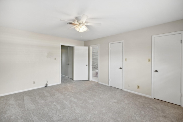 unfurnished bedroom with ceiling fan, ensuite bathroom, light carpet, and two closets