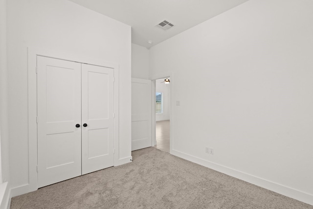 unfurnished bedroom with light carpet and a closet