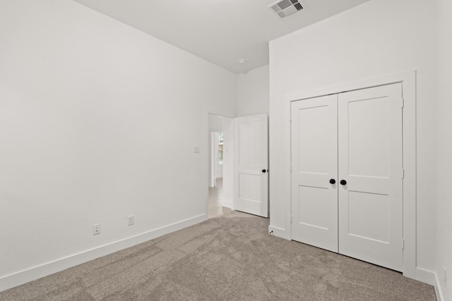 unfurnished bedroom featuring light carpet and a closet