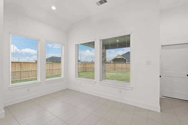 spare room with vaulted ceiling and light tile patterned flooring