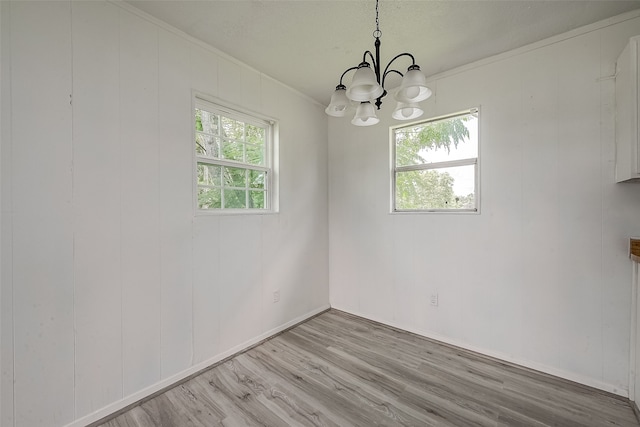 unfurnished dining area featuring an inviting chandelier and light hardwood / wood-style flooring