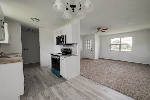 kitchen featuring white cabinetry, light carpet, electric range oven, sink, and tasteful backsplash