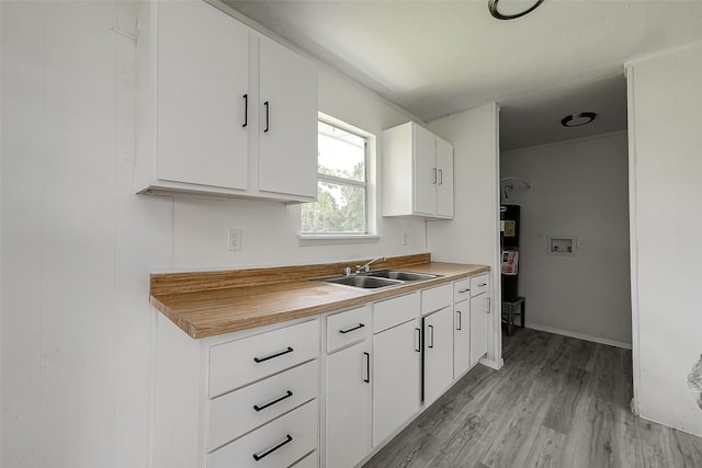 kitchen featuring sink, white cabinets, light wood-type flooring, and water heater