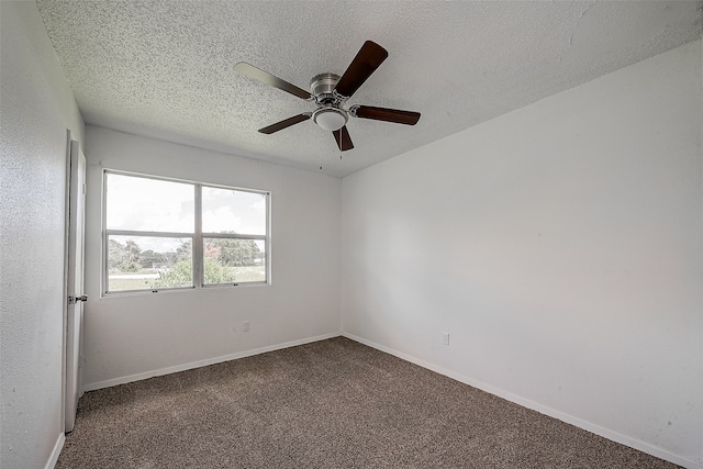 spare room featuring a textured ceiling, dark colored carpet, and ceiling fan