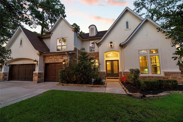 french country home with a yard, french doors, and a garage